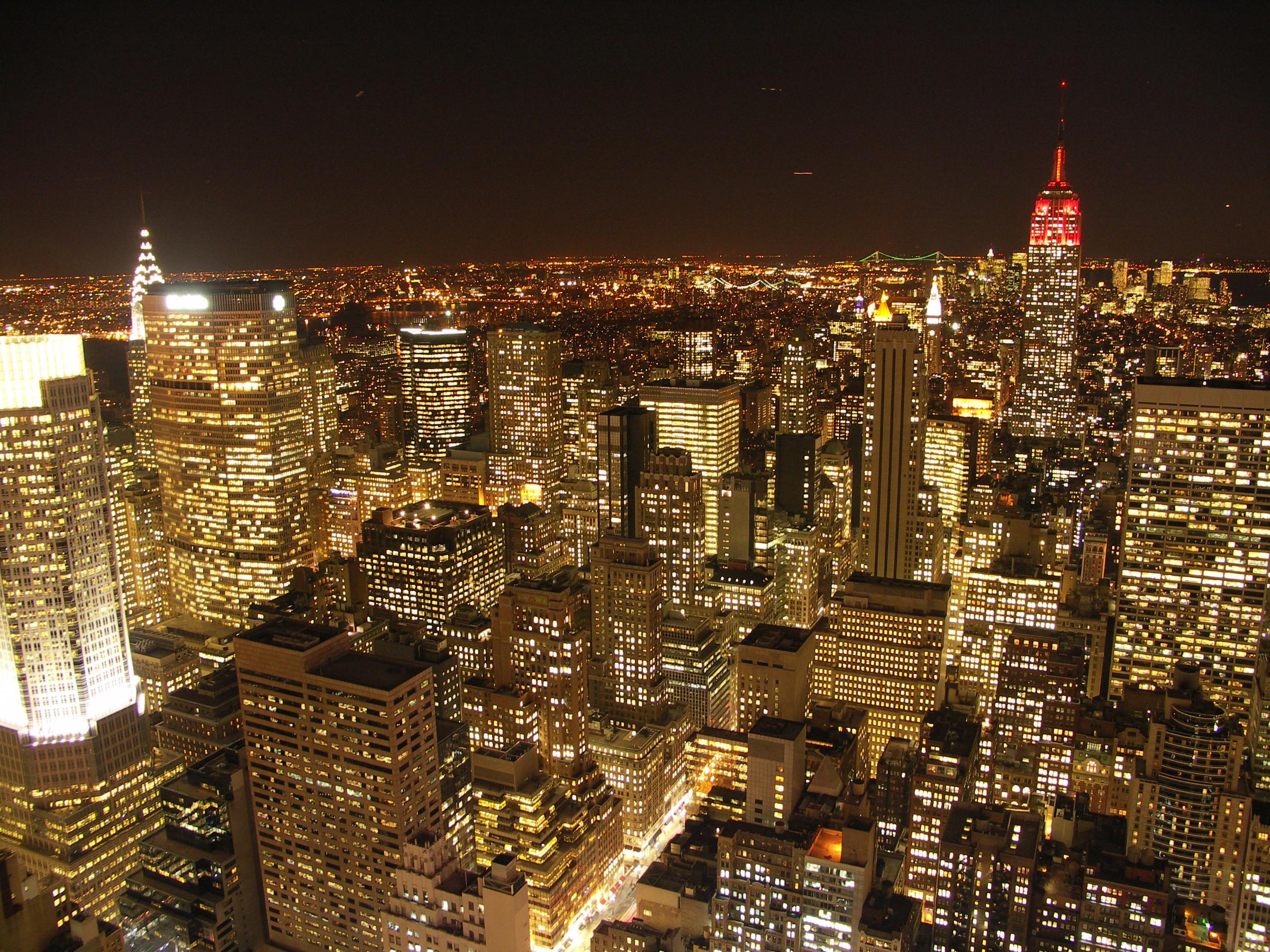 New York City skyline at night with bright lights and tall buildings.