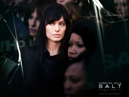 A striking HD wallpaper featuring Angelina Jolie from the movie Salt, showcasing a mysterious atmosphere with a focus on her intense gaze amidst a shadowy backdrop.