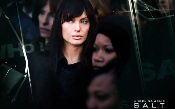 A striking HD wallpaper featuring Angelina Jolie from the movie Salt, showcasing a mysterious atmosphere with a focus on her intense gaze amidst a shadowy backdrop.