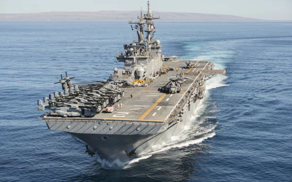The USS Essex (LHD 2), an amphibious assault ship and aircraft carrier, sails through calm waters with helicopters on deck in this 4K Ultra HD military wallpaper.