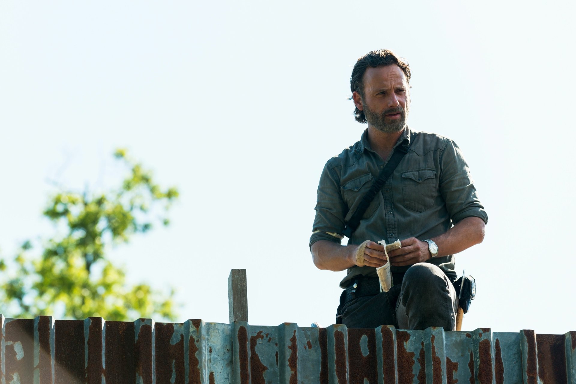 Rick Grimes, played by Andrew Lincoln in The Walking Dead, sits thoughtfully on a brick wall in this 4K Ultra HD PC desktop wallpaper.