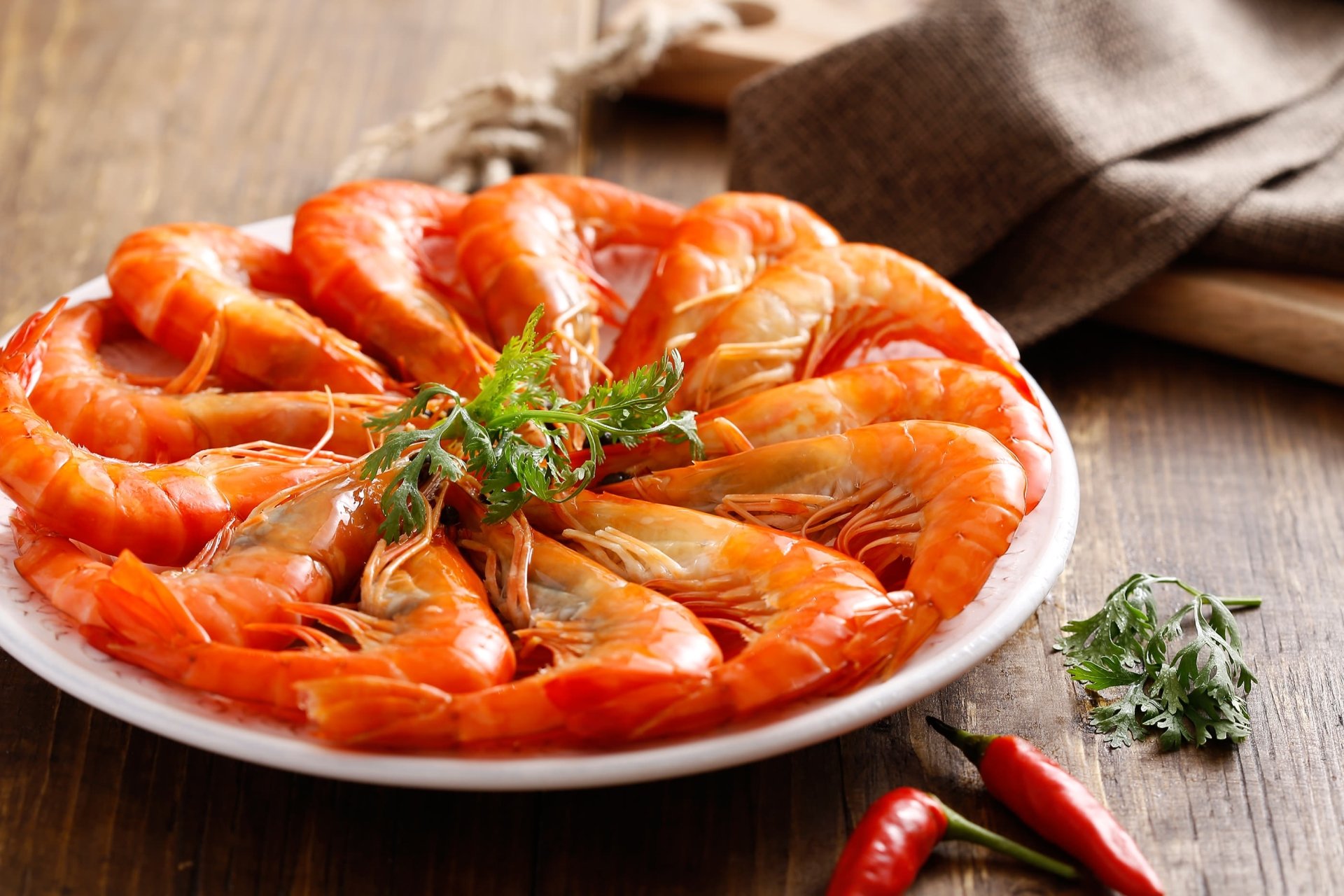 2K Quad HD PC desktop wallpaper and background: close-up of cooked shrimp on a white plate, garnished with herbs and red chilies — seafood food.