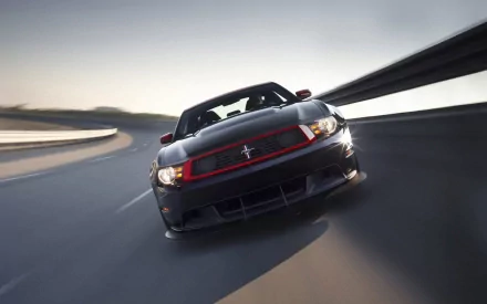 A sleek black Ford Mustang Boss 302 accelerates on a winding road, showcasing its muscular design and powerful presence in this stunning HD desktop wallpaper.