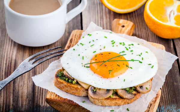 A vibrant 4K Ultra HD still life showing breakfast with toast topped with mushrooms and a fried egg, a cup of coffee, and fresh orange slices on a wooden table.