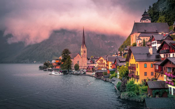 Foggy morning over the peaceful lakeside village of Hallstatt, Austria, showcasing colorful houses and a church steeple by the calm lake in 4K Ultra HD detail.