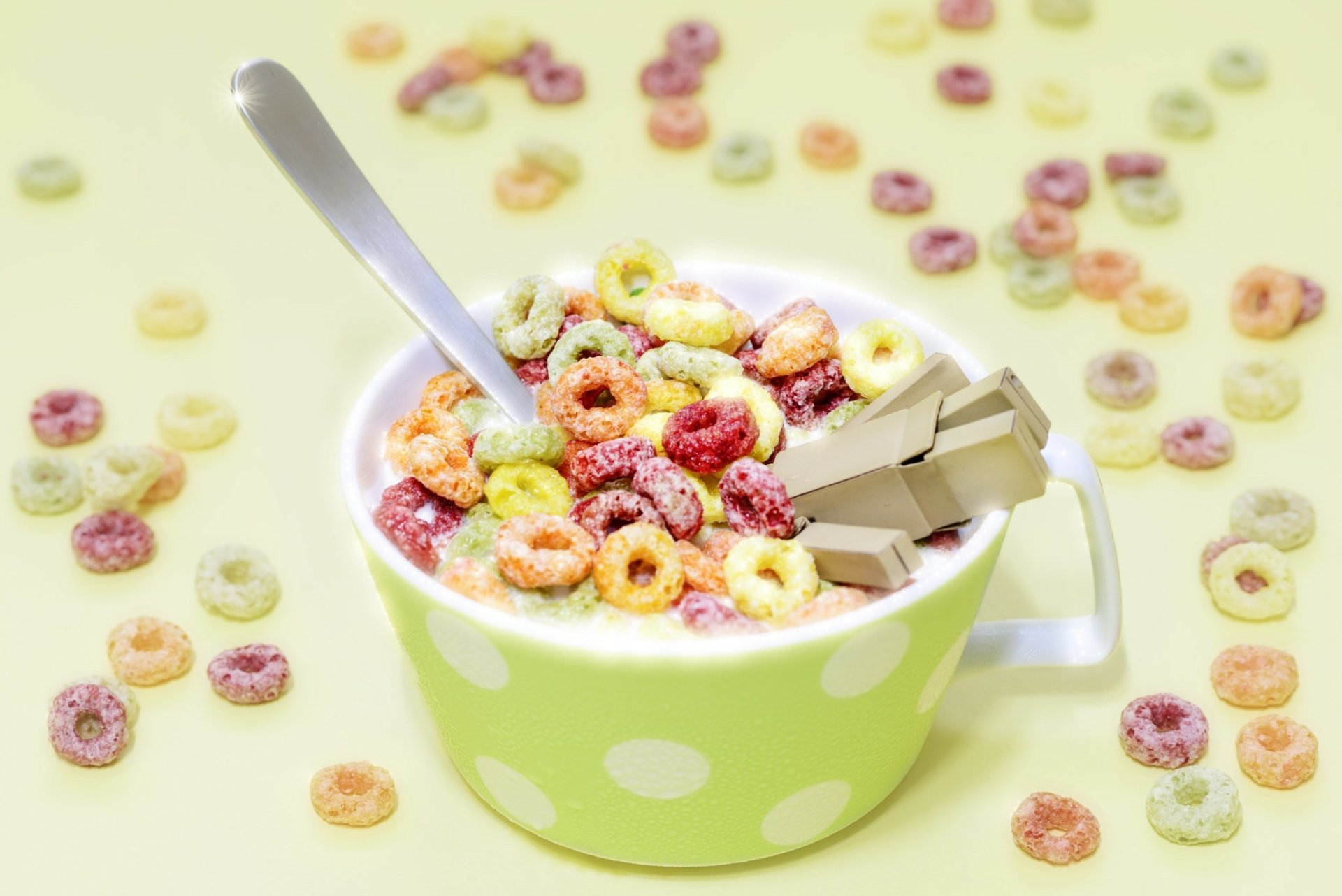 HD desktop wallpaper featuring a green polka dot cup filled with colorful cereal, milk, chocolate pieces, and a Danbo figure amidst scattered cereal loops.