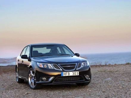 HD desktop wallpaper featuring a sleek Saab car parked near a coastal landscape under a soft pastel sky.
