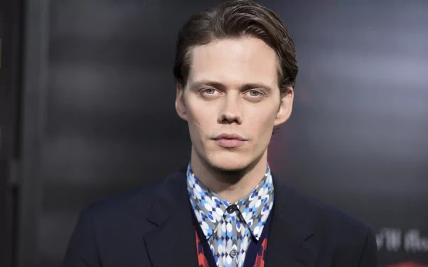HD PC desktop wallpaper featuring Swedish actor and celebrity Bill Skarsgård in a patterned shirt and dark jacket against a blurred background.