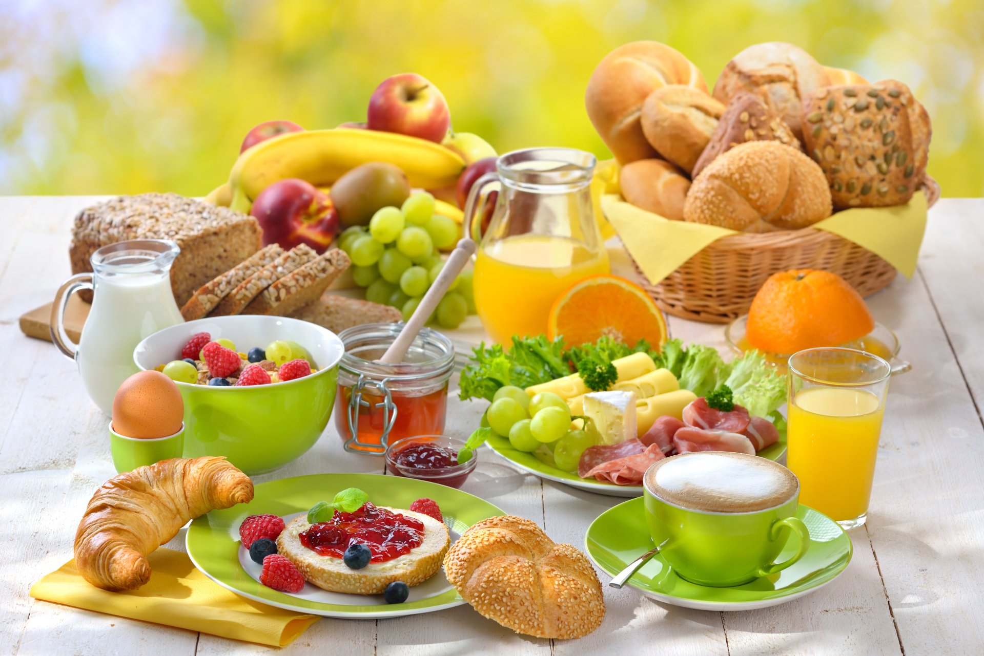 A vibrant 4K Ultra HD still life of a breakfast spread featuring juice, coffee, viennoiserie, fresh fruit, and various breakfast foods on a bright table.