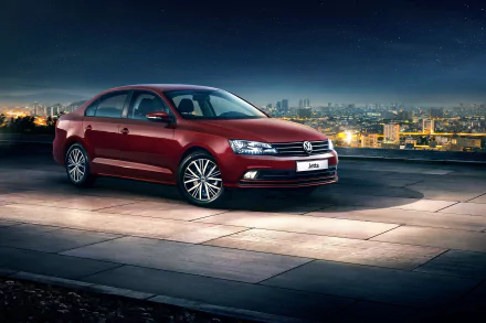 A red Volkswagen Jetta compact car parked at night on an open rooftop with a city skyline in the background, shown in an HD desktop wallpaper.