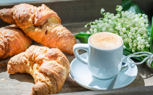 5K Ultra HD PC desktop wallpaper: golden croissants and a white coffee cup on a saucer, a viennoiserie breakfast scene.