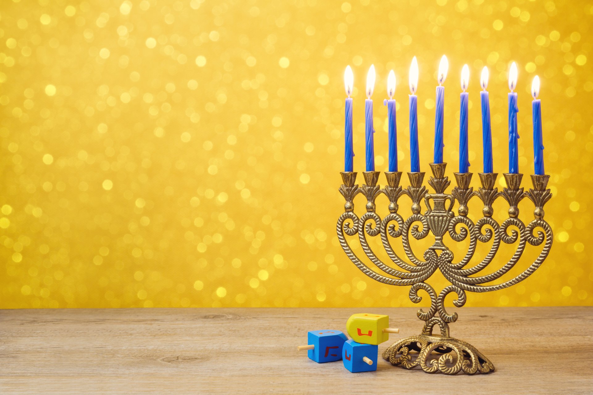 A golden Hanukkah menorah with blue candles lit against a sparkling golden background, featured as a 4K Ultra HD holiday desktop wallpaper.