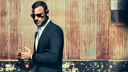 HD wallpaper of a man styled akin to Ray Donovan, sporting a suit and sunglasses, against a rusty metal backdrop.