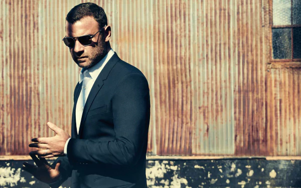 HD wallpaper of a man styled akin to Ray Donovan, sporting a suit and sunglasses, against a rusty metal backdrop.