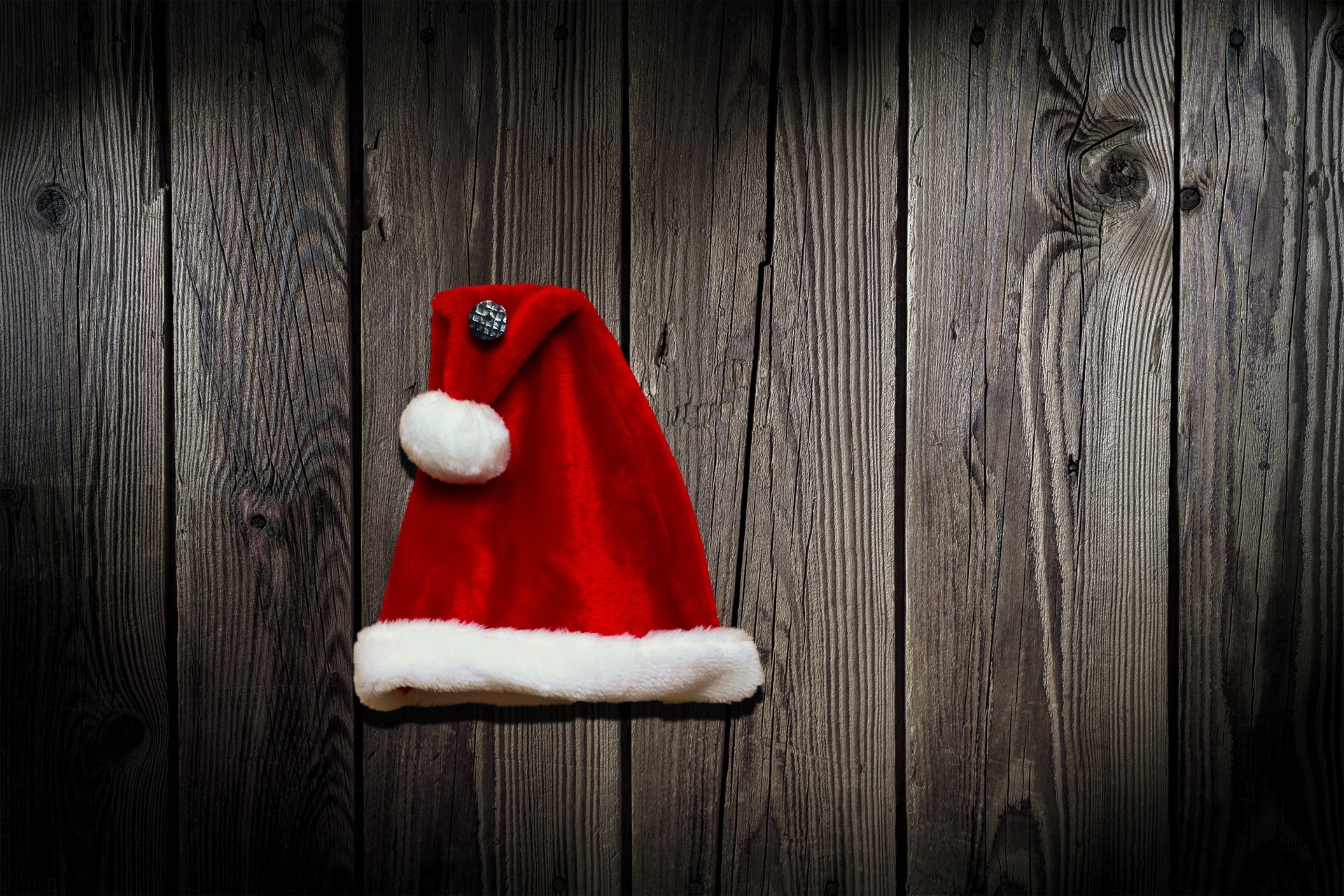 Red Santa hat with white trim on dark wooden planks — festive Christmas holiday 4K Ultra HD PC desktop wallpaper background.