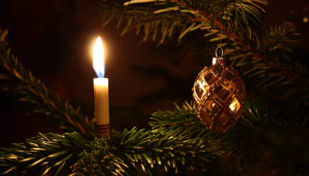 HD wallpaper: A lit candle and a gold Christmas ornament hanging on a pine branch, adding a warm holiday ambiance.