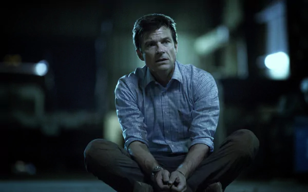 HD wallpaper featuring a character from Ozark, portrayed by Jason Bateman, sitting pensively in a dimly lit setting.