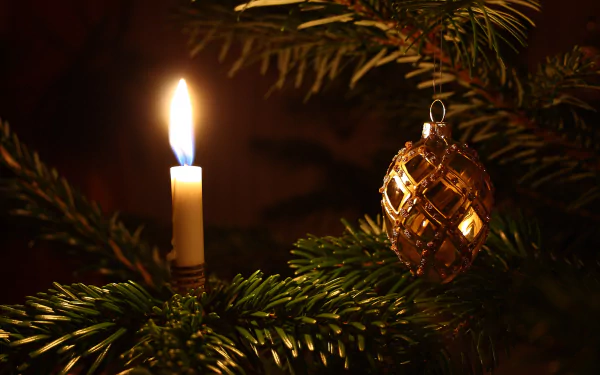 HD wallpaper: A lit candle and a gold Christmas ornament hanging on a pine branch, adding a warm holiday ambiance.