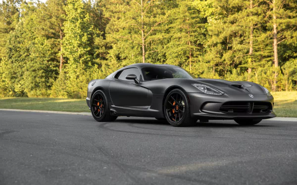 Silver Dodge Viper GTS parked on a paved road with a forest backdrop, showcased as an HD desktop wallpaper featuring this iconic sports car.