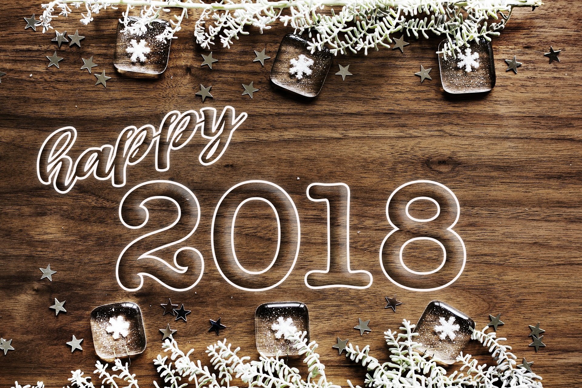 A festive HD desktop wallpaper celebrating New Year 2018, featuring Happy 2018 text surrounded by decorations and stars on a wooden background.