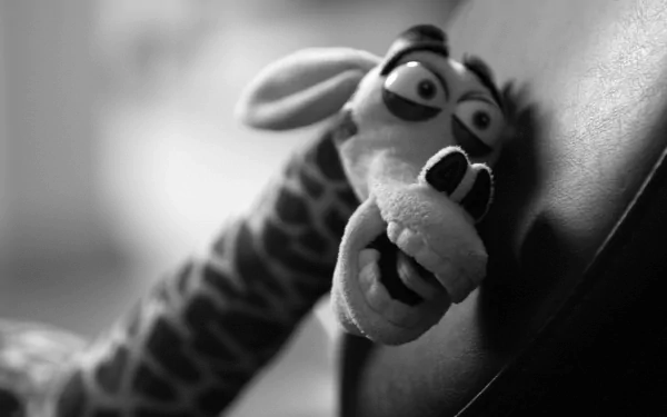 A funny, strange close-up of a wide-eyed giraffe puppet with an exaggerated expression, captured as an HD PC desktop wallpaper background in black and white.