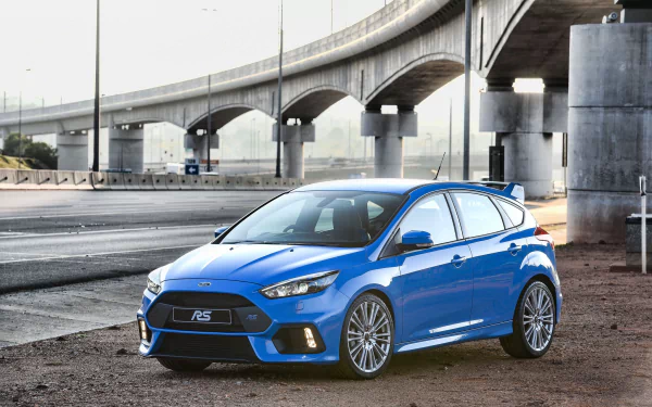 Blue Ford Focus compact hatchback parked beneath a concrete overpass, captured as a high-definition PC desktop wallpaper and background.