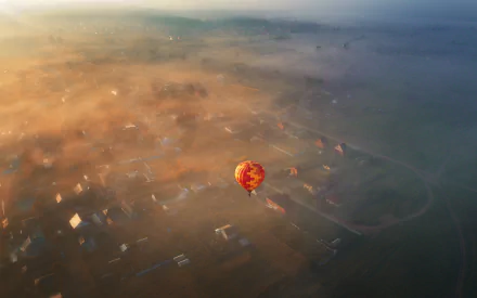 Aerial view of a colorful hot air balloon floating over a misty landscape, captured in HD for a stunning desktop wallpaper and background.