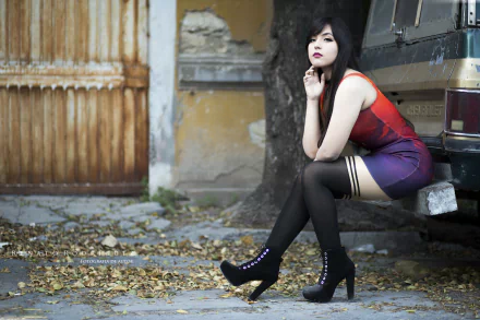 Woman with black hair and brown eyes, wearing lipstick, a dress, and high heels, posing for a cosplay photoshoot titled Judy's Lullaby. HD desktop wallpaper. She sits by an old vehicle on a leaf-strewn street.