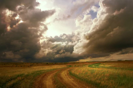 HD PC desktop wallpaper background: dramatic storm clouds over a grassy field with a winding dirt road in a wide nature landscape.