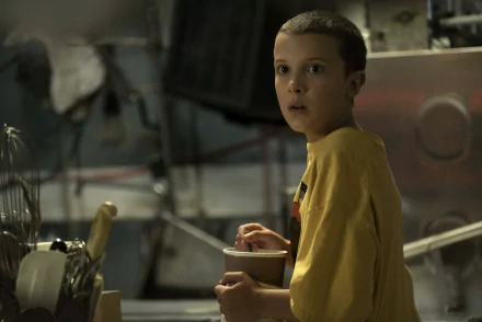 HD desktop wallpaper featuring Eleven from Stranger Things, portrayed by Millie Bobby Brown, captured in a dimly lit, suspenseful TV show scene.