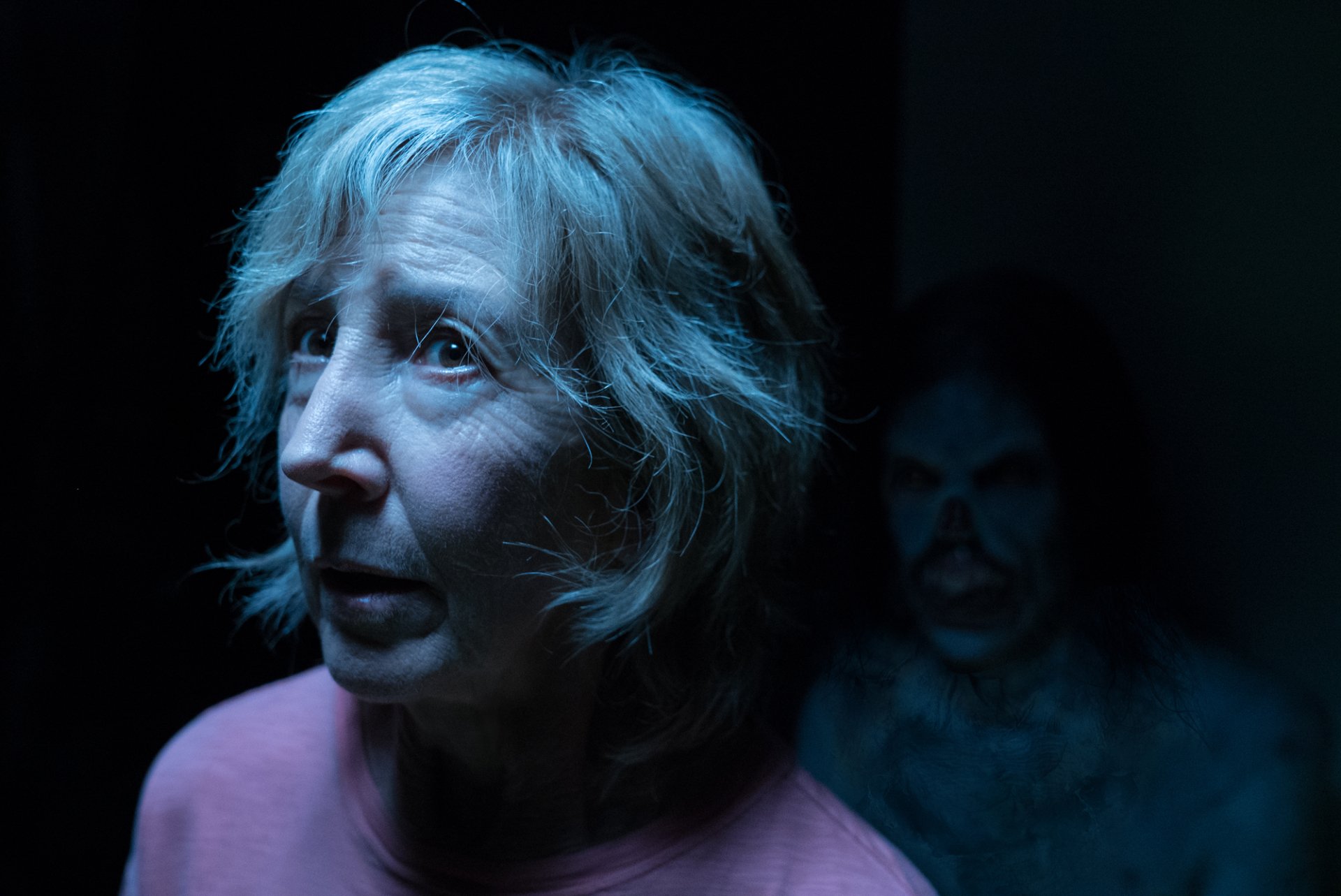 HD desktop wallpaper of a scene from Insidious: The Last Key with a fearful woman and a ghostly figure in the background.