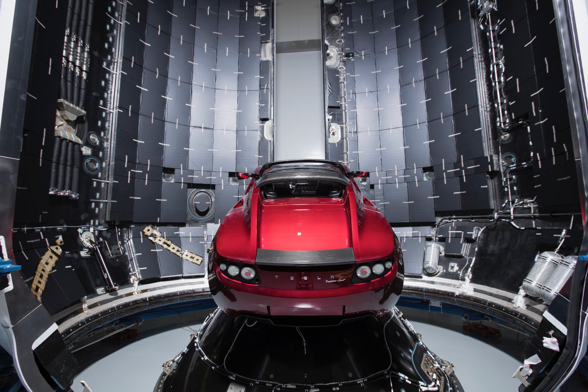 HD desktop wallpaper featuring a red Tesla Roadster inside the Falcon Heavy rocket payload bay, highlighting advanced vehicle and space technology.