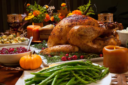 HD desktop wallpaper of a Thanksgiving meal featuring a roasted turkey, green beans, cranberries, stuffing, and candles, with a festive holiday background.