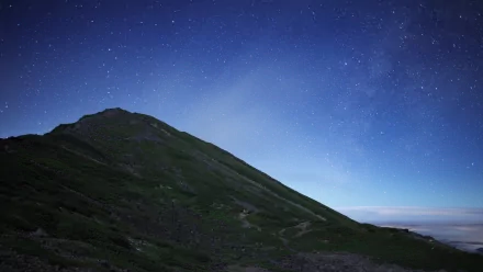 HD PC desktop wallpaper background — nature mountain scene: a dark mountain ridge silhouetted beneath a star-filled sky with a soft horizon glow.