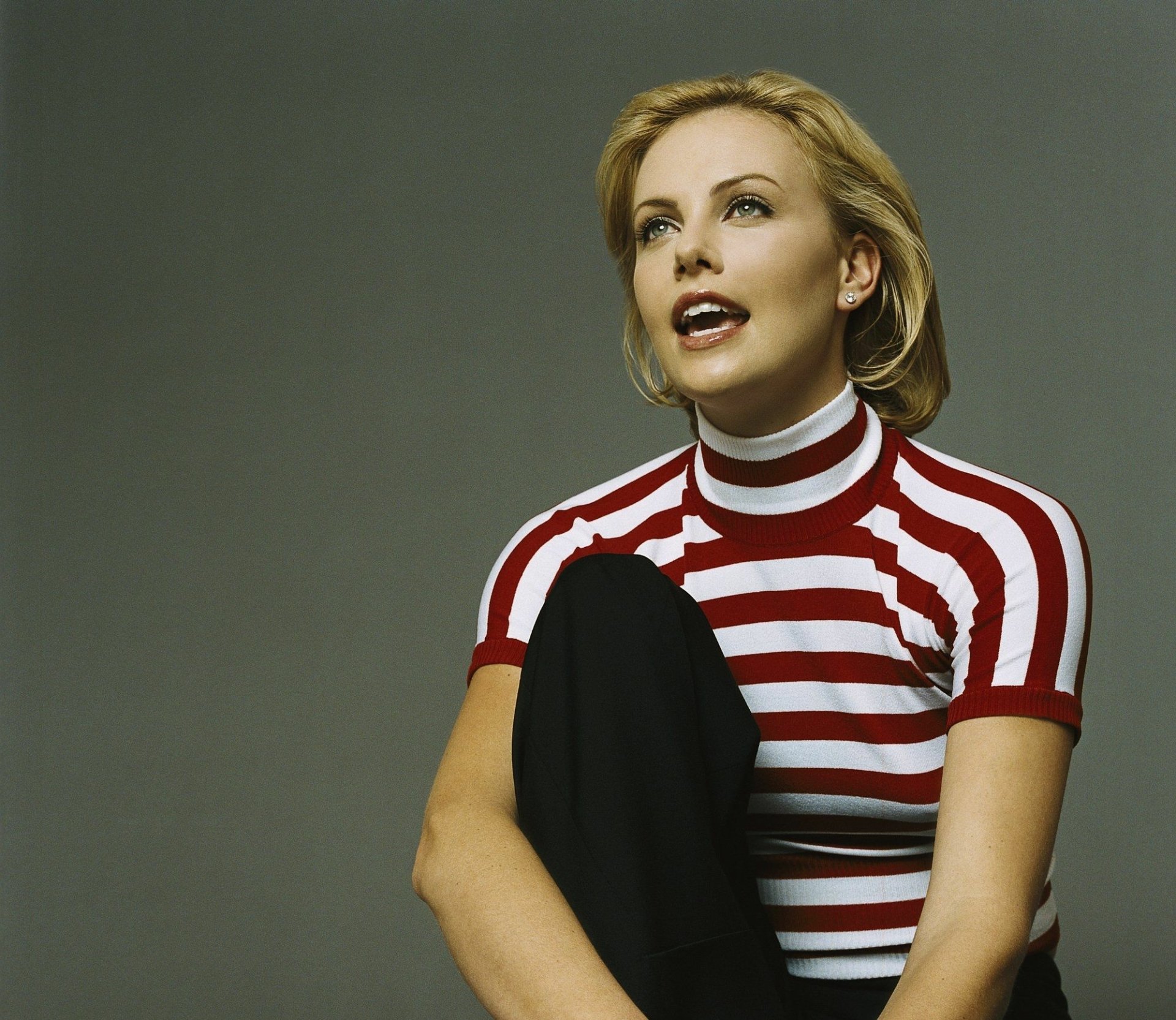HD desktop wallpaper featuring South African actress Charlize Theron with short blonde hair wearing a red and white striped top against a plain background.