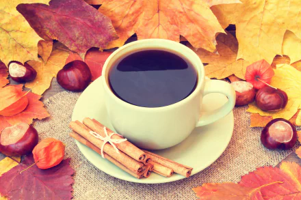 A 4K Ultra HD desktop wallpaper showing a cup of coffee with cinnamon sticks on a saucer, surrounded by colorful autumn leaves and chestnuts.
