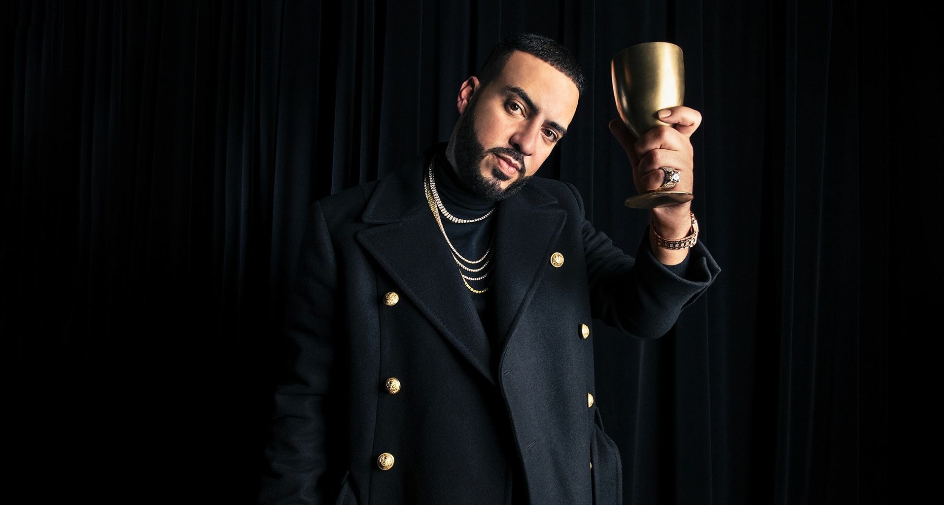 HD desktop wallpaper featuring a person in a stylish black jacket holding a gold cup, against a dark background.