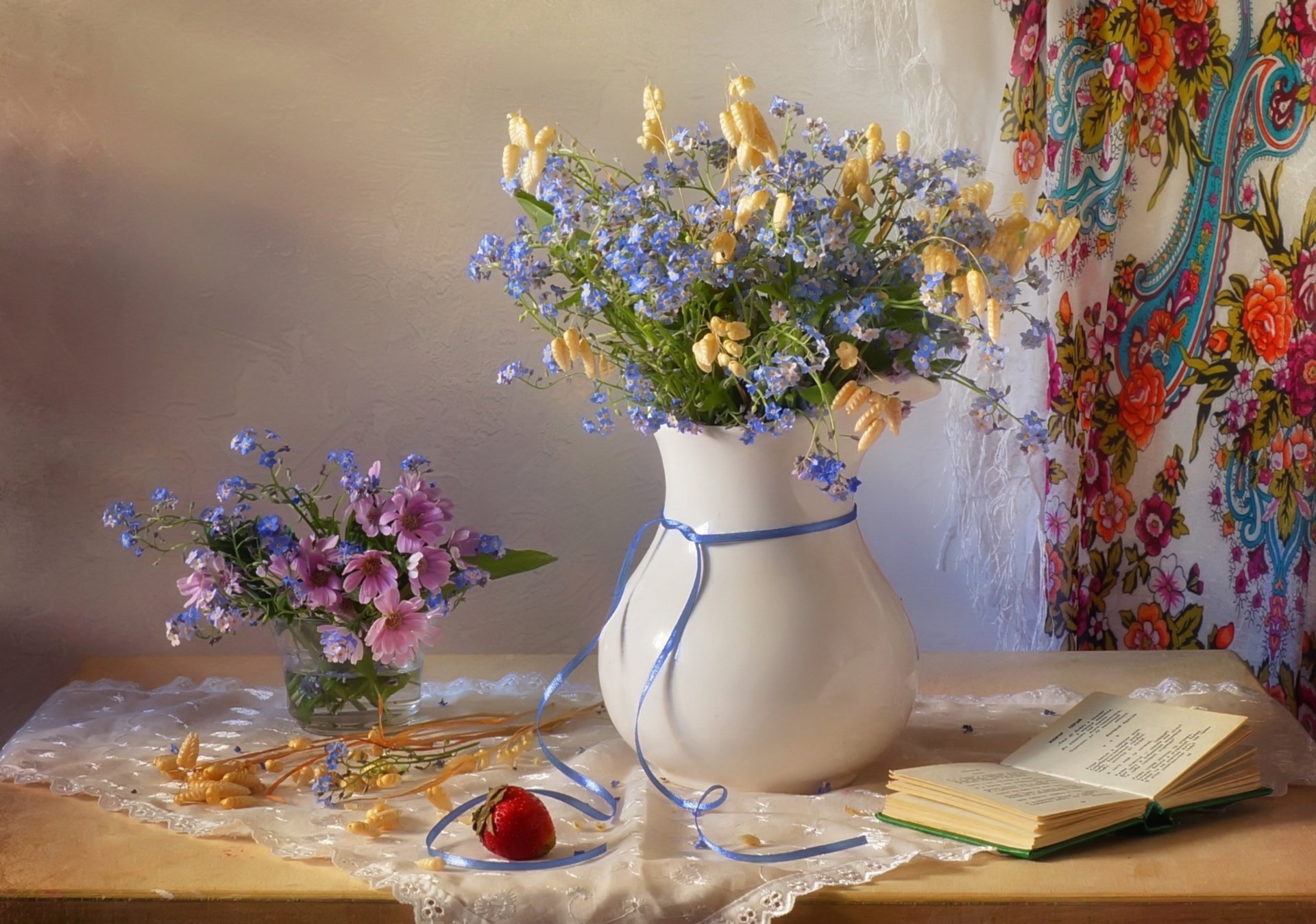 Still life photography of a flower arrangement in a white vase with a blue ribbon, accompanied by a smaller bouquet, an open book, and a strawberry on a table, HD desktop wallpaper.
