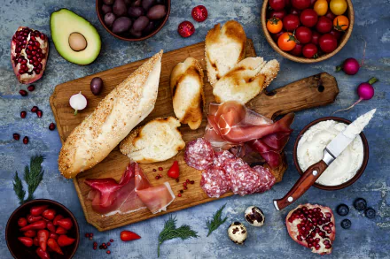 4K Ultra HD PC desktop wallpaper still life of food: sliced salami and cured meat, crusty bread, cheese, avocado fruit, olives and berries artfully arranged on a wooden board.