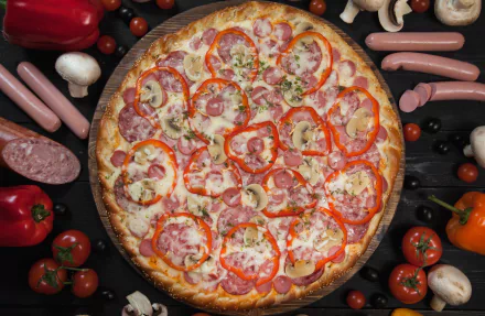 HD desktop wallpaper featuring a colorful pizza topped with sausage, tomato, and pepper, surrounded by fresh ingredients like mushrooms, peppers, and meat in a still life arrangement.
