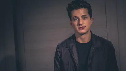 HD desktop wallpaper featuring a portrait of a man with a subdued expression, wearing a dark jacket, against a textured background.