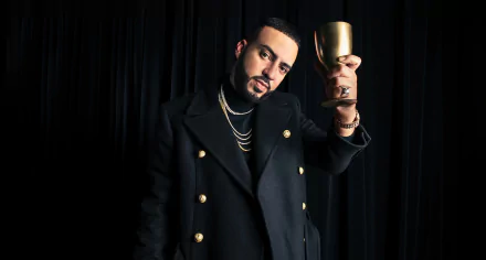 HD desktop wallpaper featuring a person in a stylish black jacket holding a gold cup, against a dark background.
