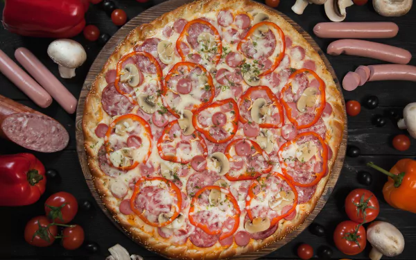 HD desktop wallpaper featuring a colorful pizza topped with sausage, tomato, and pepper, surrounded by fresh ingredients like mushrooms, peppers, and meat in a still life arrangement.
