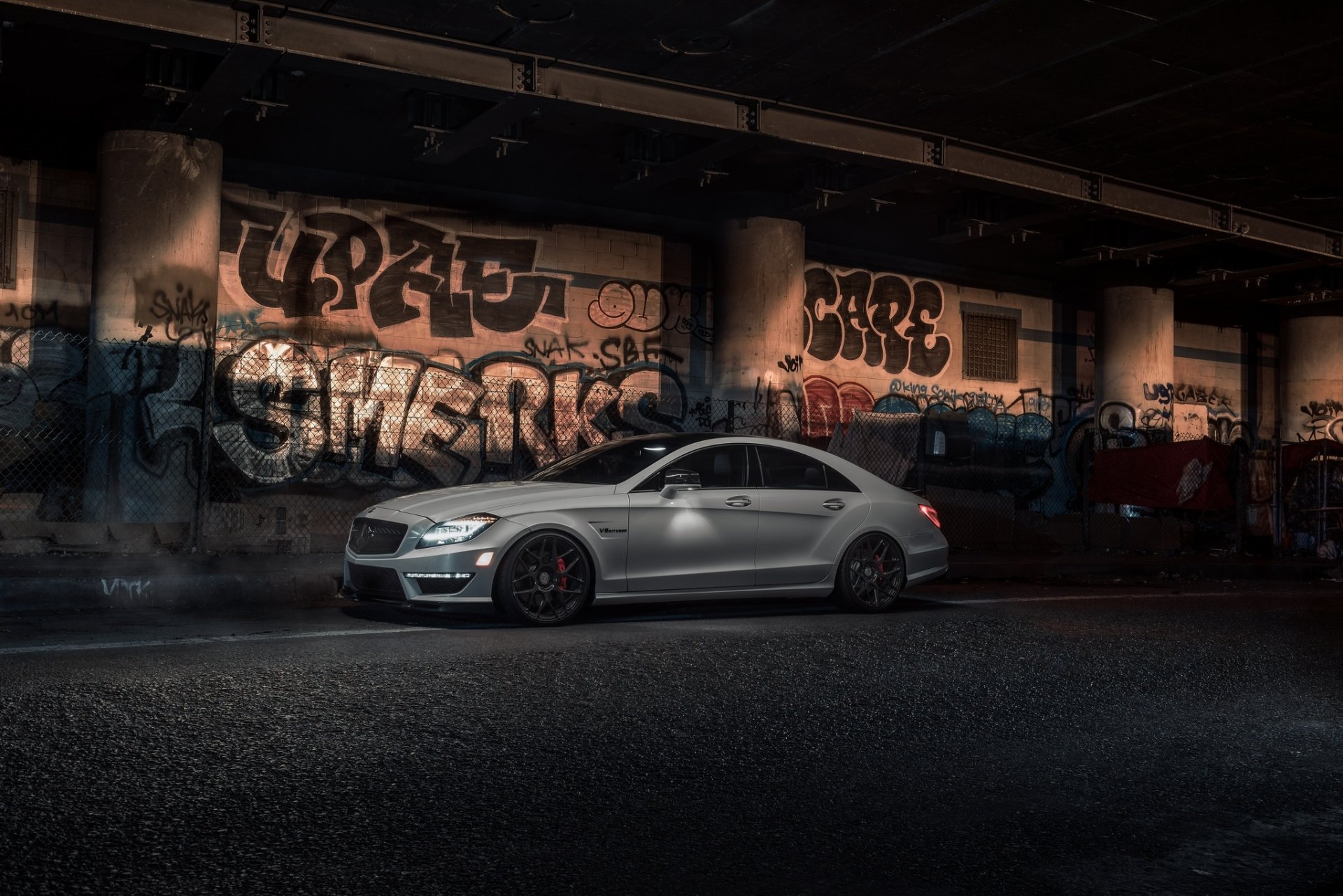 A silver Mercedes-Benz CLS-Class parked in an urban setting with vibrant graffiti on the concrete walls, captured in high-definition as a PC desktop wallpaper.