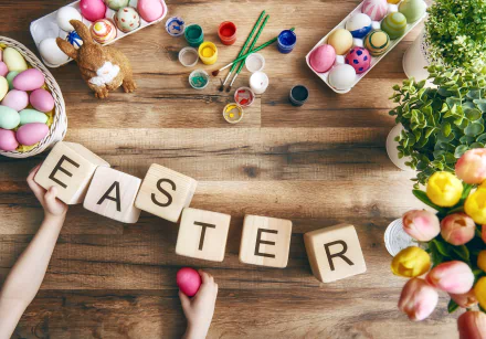 HD still life desktop wallpaper featuring colorful Easter eggs, paint jars, flowers, and wooden blocks spelling EASTER on a rustic wooden table celebrating the holiday.