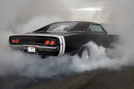 A classic black Dodge Charger RT muscle car performs a smoky burnout, captured in HD for a dramatic desktop wallpaper background.