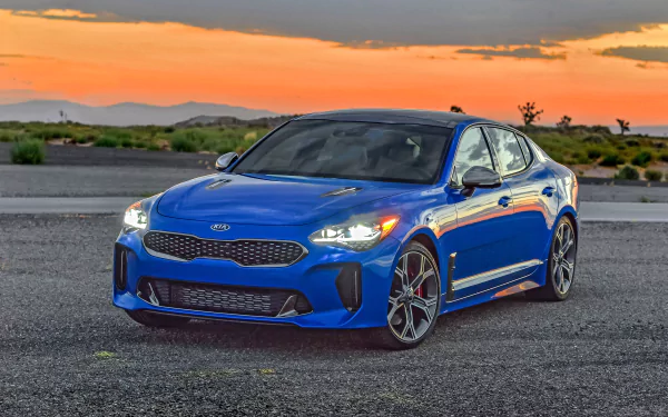 Blue Kia Stinger vehicle parked on asphalt at sunset — striking 2K Quad HD PC desktop wallpaper and background.