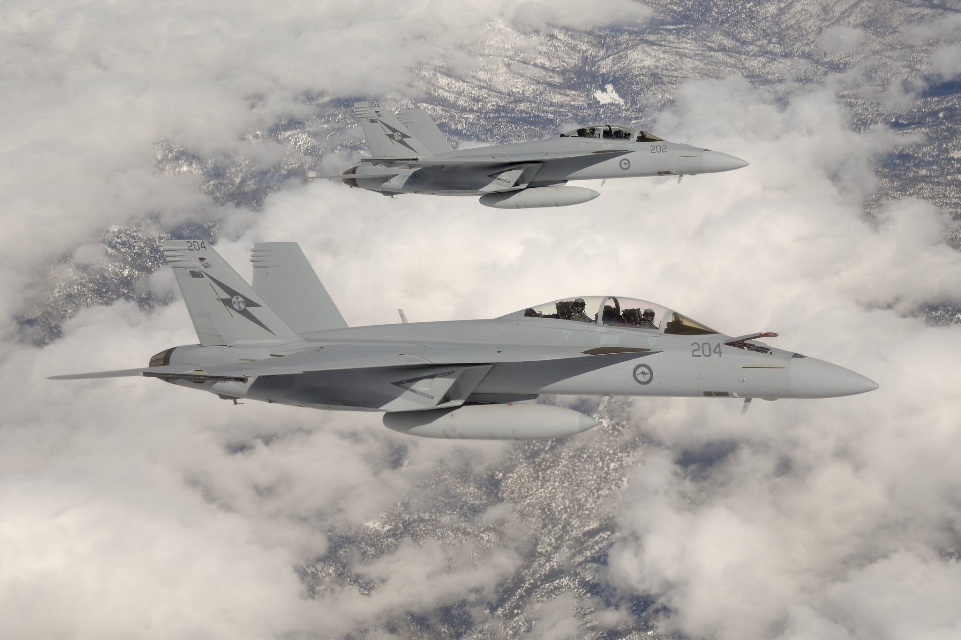 Two McDonnell Douglas CF-18 Hornet military jet fighters fly above clouds, captured in high-definition as a striking warplane desktop wallpaper.