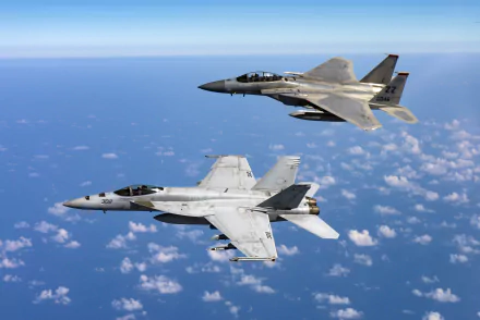HD desktop wallpaper featuring a Boeing F/A-18E/F Super Hornet and a McDonnell Douglas F-15 Eagle jet fighter flying over a vast sky, showcasing the sleek design of military warplanes.