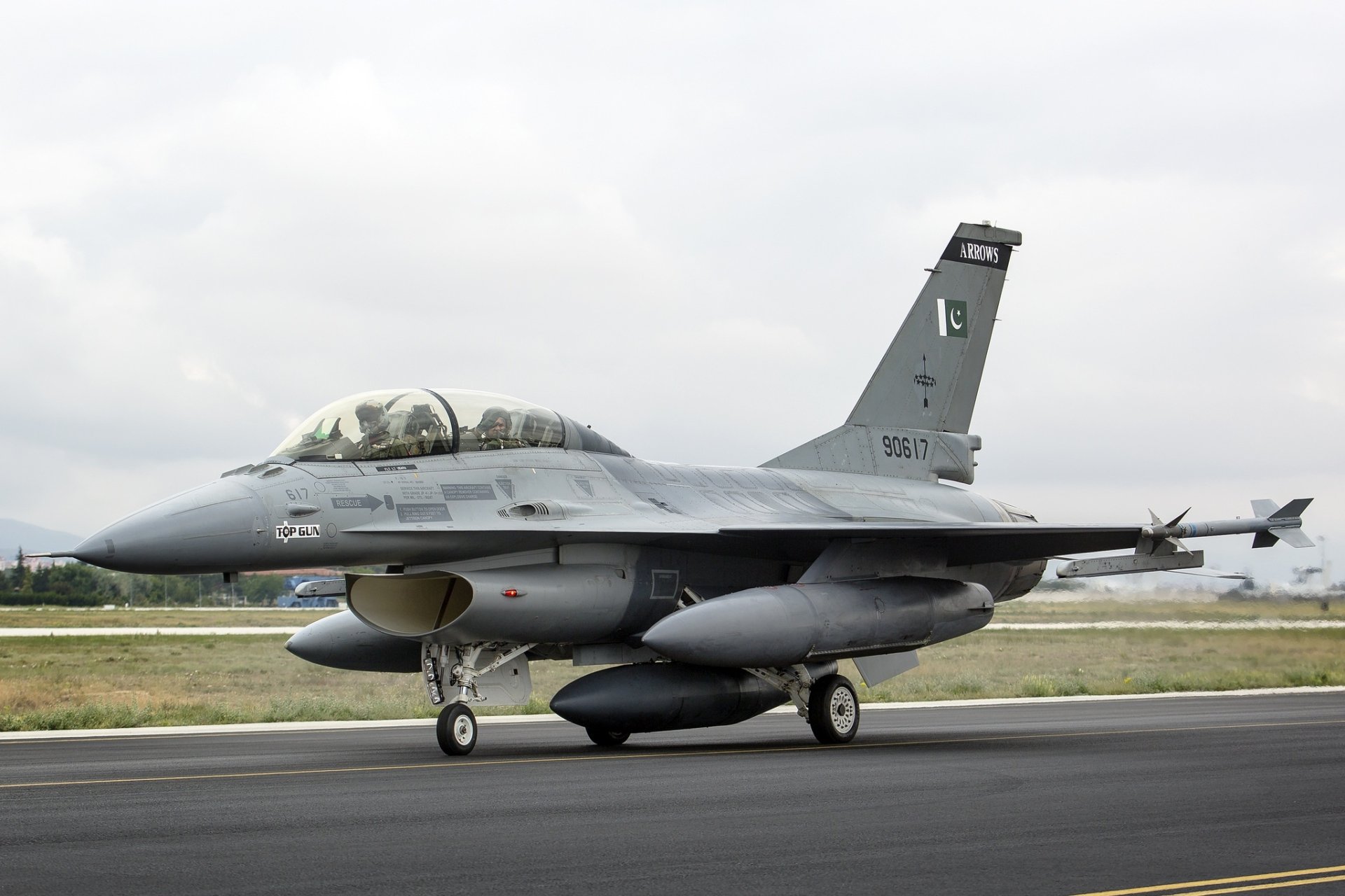 HD desktop wallpaper featuring a General Dynamics F-16 Fighting Falcon jet fighter, a sleek military warplane on the runway under a cloudy sky.